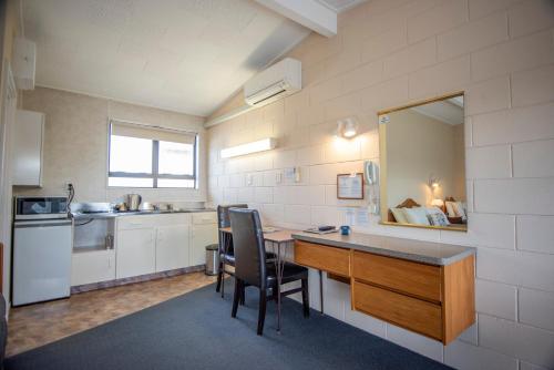 a kitchen with a table and chairs in a room at Tuki Tuki Motel in  Waipukurau