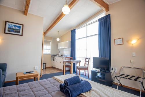 a bedroom with a bed and a living room at Tuki Tuki Motel in  Waipukurau