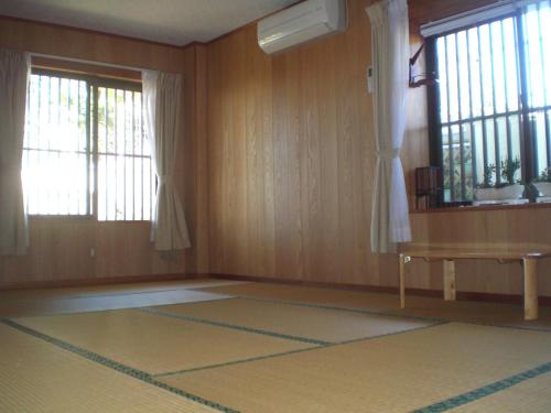 an empty room with a table and two windows at Minshuku Shizu in Onna