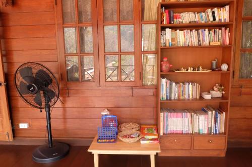 a fan sitting on a table in a room with books at Ashi Guesthouse Chiangdao in Chiang Dao