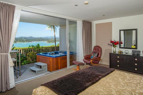a bedroom with a tub and a balcony with a view at Tarlton's Lodge in Paihia