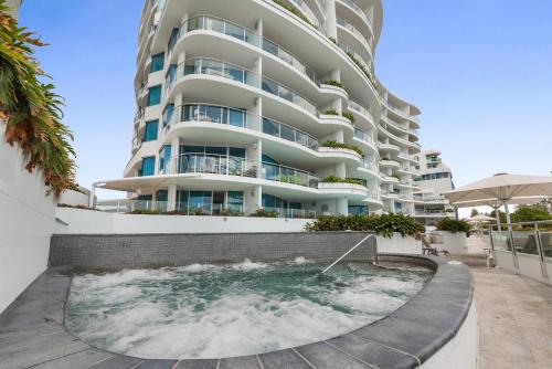 a building with a swimming pool in front of a building at Mantra Sirocco in Mooloolaba