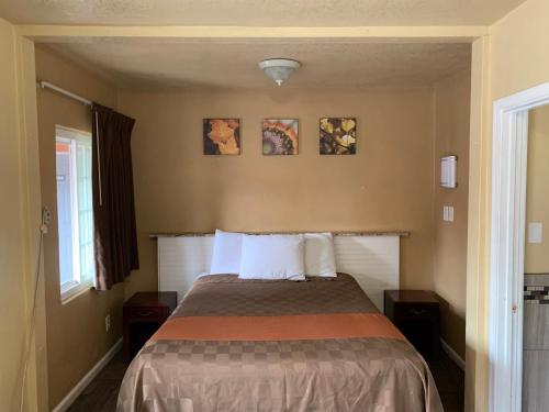 a bedroom with a bed and two pictures on the wall at SunLight Motel Long Beach in Long Beach