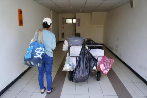 a woman walking down a hallway with a cart of bags at Paris Motel in Mailiao