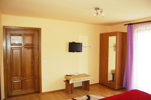 a room with a bed and a door and a table at Pensiunea Sarah Bran in Bran
