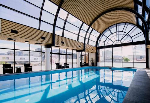 a swimming pool in a building with windows at Hotel Grand Chancellor Hobart in Hobart