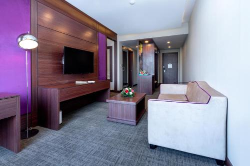 a hotel room with a couch and a tv at Becamex Hotel New City in Thu Dau Mot