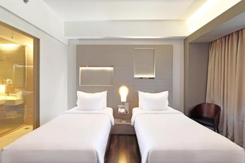 a hotel room with two beds and a desk at Swiss-Belhotel Cirebon in Cirebon