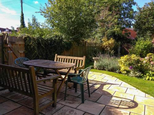 a patio with two benches and a table and chairs at Jasmine Cottage, Kelsale, sleeps 5 - Aldeburgh Coastal Cottages in Kelsale