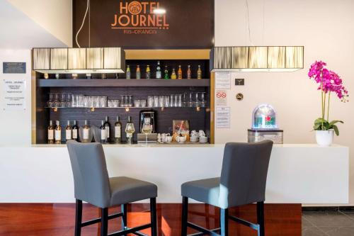 a bar with two chairs and a counter with wine bottles at Best Western Hôtel Journel Paris Sud in Ris-Orangis