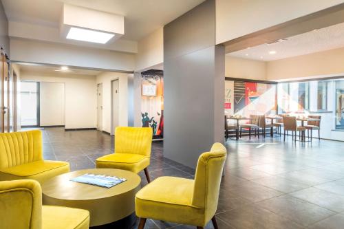 a waiting room with yellow chairs and a table and chairs at Best Western Hôtel Journel Paris Sud in Ris-Orangis