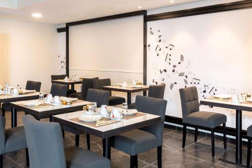 a dining room with tables and chairs with birds on the wall at Best Western Hôtel Journel Paris Sud in Ris-Orangis