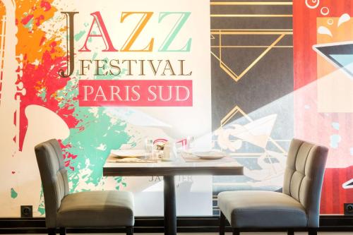 a restaurant with a table and chairs in front of a mural at Best Western Hôtel Journel Paris Sud in Ris-Orangis