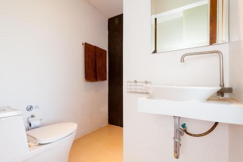 a white bathroom with a sink and a toilet at Coral View Resort in Koh Tao