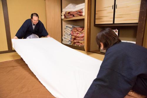 two people are working on a piece of cloth at Kyo no Minshuku Ohara no Sato in Kyoto