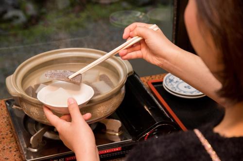 a woman stirring a pot with a pair of chopsticks at Kyo no Minshuku Ohara no Sato in Kyoto