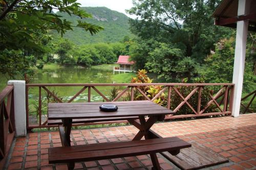 a wooden table and bench on a balcony with a river at River Kwai Park & Resort in Chongsadao