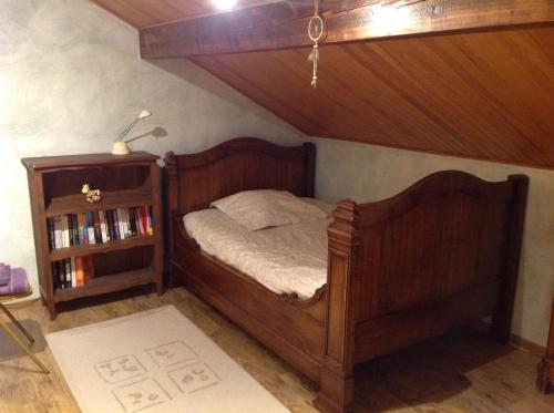 a bedroom with a wooden bed and a book shelf at La Sapotine in Étrembières