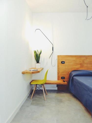 a bedroom with a bed and a desk with a yellow chair at Casa Anna in Ilbono