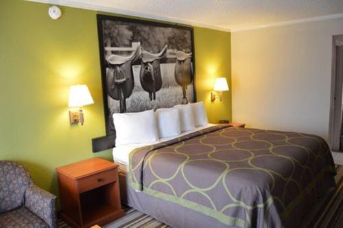 a hotel room with a bed with a painting on the wall at Super 8 by Wyndham Longview/North in Longview