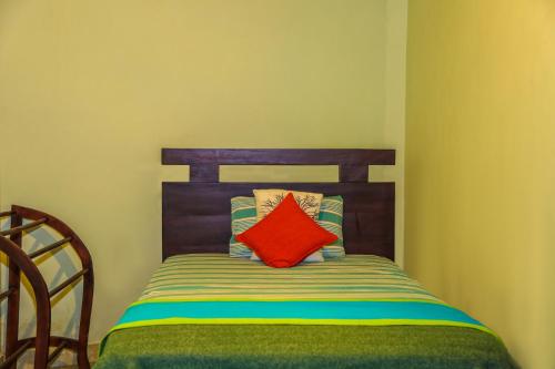 a bed with a wooden head board with a red pillow at Kandyan Hideout in Kandy