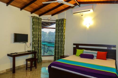 a bedroom with a bed and a desk and a television at Kandyan Hideout in Kandy