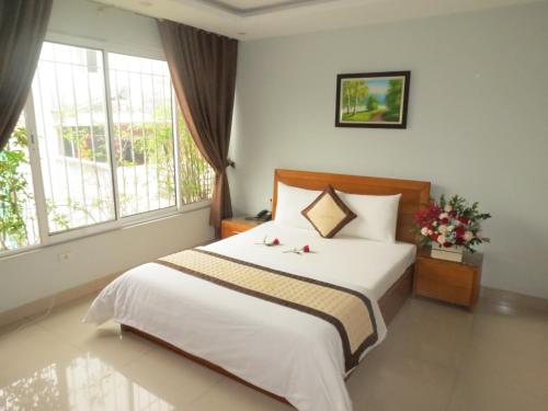 Un dormitorio con una gran cama blanca con flores. en Green Hotel, en Hanói