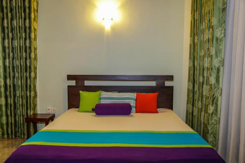 a bedroom with a bed with colorful pillows at Kandyan Hideout in Kandy