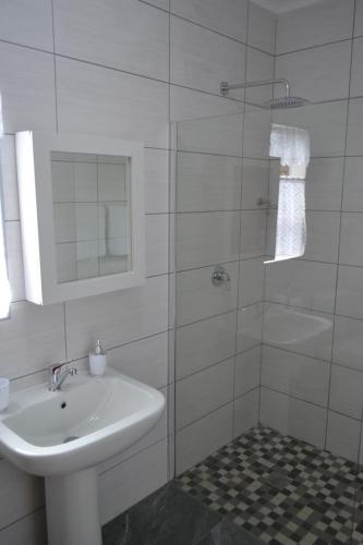 a white bathroom with a sink and a shower at Apple Orchard Cottage in Harrismith
