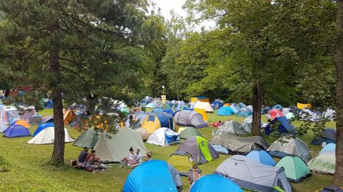 a large group of people sitting in a field with tents at Hotel Mladost in Tjentište