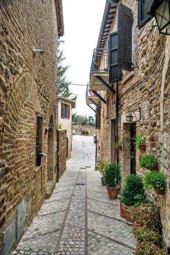 an alley between two brick buildings with potted plants at Vecchio Forno Casa Vacanze in Montefalco