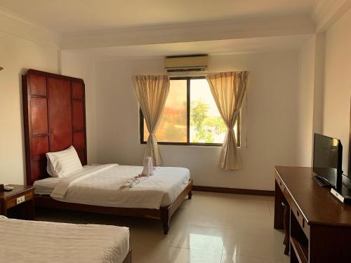 a hotel room with two beds and a window at Champey Villa in Siem Reap