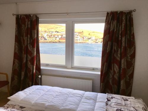 a bedroom with a window with a view of the water at The Atlantic view guest house, Sandavagur, Faroe Islands in Sandavágur