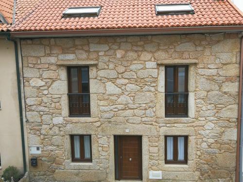 a stone building with four windows and a red roof at Casa rural Camelle Casa dos avós in Camariñas