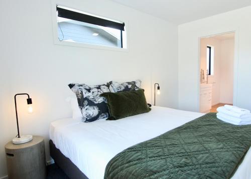 a bedroom with a large bed with a green blanket at 4 - Charming Space, Just a Stone Throw from Central Wanaka in Wanaka
