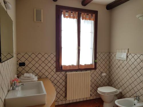 baño con lavabo y aseo y ventana en Ca l'oasi, en San Donà di Piave