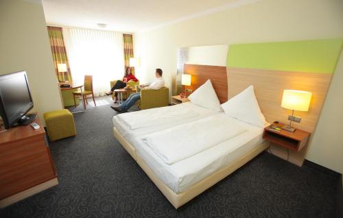 a hotel room with a bed and a tv at Pfalzhotel Asselheim in Asselheim