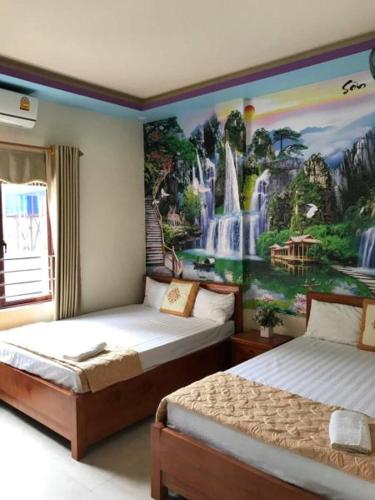 a bedroom with two beds with a waterfall mural on the wall at Trang Toan Hotel in Cat Ba