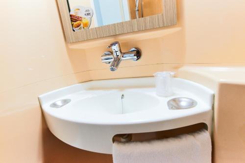 bagno con lavandino bianco e specchio di Premiere Classe Roissy CDG - Paris Nord 2 - Parc des Expositions a Roissy en France