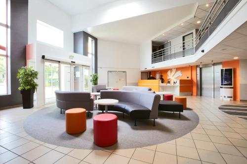 un hall de bureau avec des chaises, des tables et des fenêtres dans l'établissement Premiere Classe Roissy CDG - Paris Nord 2 - Parc des Expositions, à Roissy-en-France