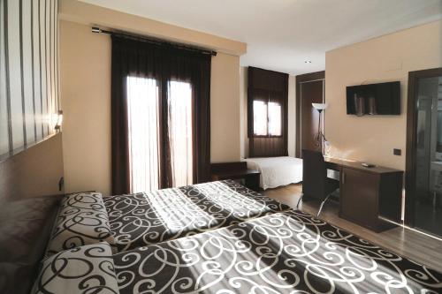 a hotel room with a large bed and a television at Hotel Ciudad de Plasencia in Plasencia