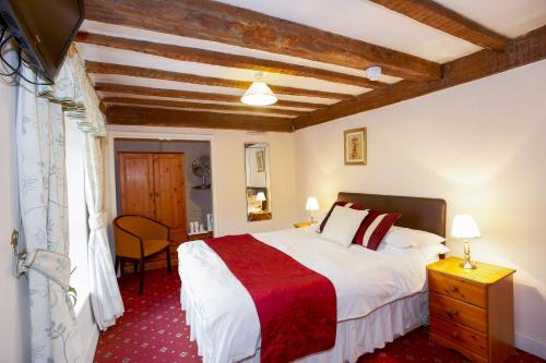 - une chambre avec un grand lit et un tapis rouge dans l'établissement Seven Stars, à Hay-on-Wye