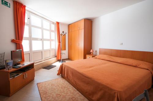a bedroom with a bed and a tv and a window at Studio and Room Lena in Dubrovnik