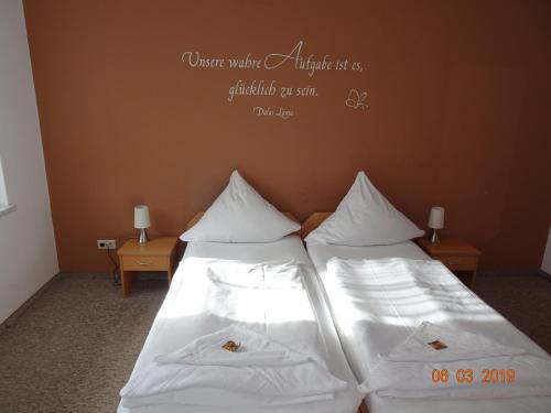 Gasthaus Stadt Bad Sulza في باد سولزا: سريرين في غرفة ذات أغطية ووسائد بيضاء