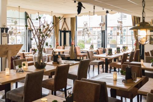 een restaurant met houten tafels, stoelen en ramen bij Hotel de Gulden Leeuw in Workum