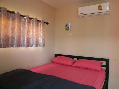 1 cama con 2 almohadas rojas en una habitación en Sripech Home en Sangkhla Buri