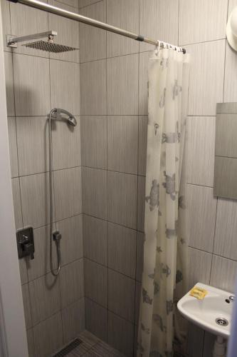 ducha con cortina de ducha y lavamanos en Galeona en Elblag