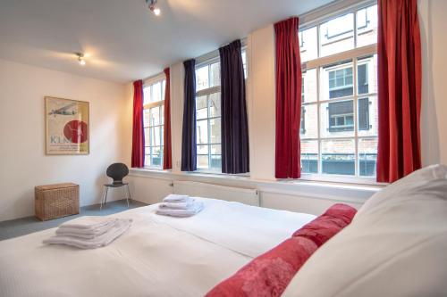 a bedroom with a white bed with red curtains at Here's Lucy in Amsterdam