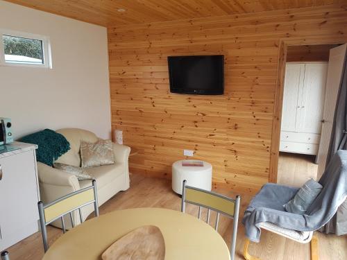 a living room with a couch and a tv on a wall at Acorn Camping and Caravan Park in Llantwit Major