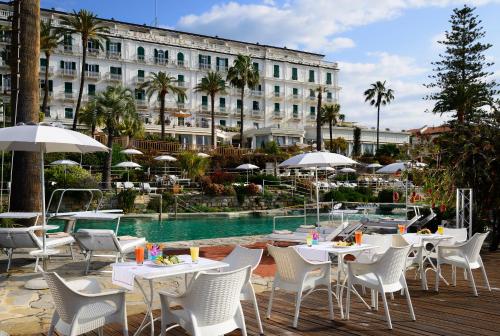 um hotel com mesas e cadeiras ao lado de uma piscina em Royal Hotel Sanremo em Sanremo